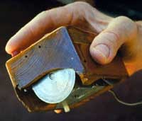 The first computer mouse held by inventor  showing the wheels which directly contact the working surface.
