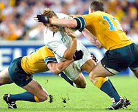 Two Australian players make a heavy tackle on an England player