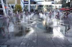 A jogger cools off in the splash fountain that forms the main centerpiece of a flat open space known as Dundas Square at the heart of downtown Toronto. This fountain was designed and built for waterplay, and undergoes strict water quality testing standards. The water is heated using solar energy picked up by special dark colored nonslip granite slabs.