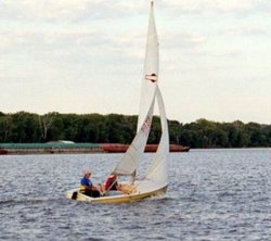 A sailboat (racing dinghy) and barge share the 