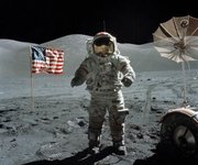 Schmitt took this picture of Cernan flanked by an American flag and their 's umbrella-shaped high-gain antenna near the beginning of their third and final excursion across the lunar surface. The prominent Sculptured Hills lie in the background while Schmitt's reflection can just be made out in Cernan's helmet.