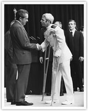 President Richard Nixon, left, greets the released John McCain, right, on crutches.