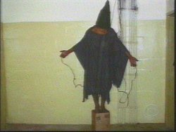 One of a series of photos taken by U.S. soldiers of Iraqi prisoners in Abu Ghraib. The hooded prisoner had wires attached to both hands and his penis, and was reportedly told that he would be electrocuted if he fell off the box he was standing on; the wires were not actually electrified.