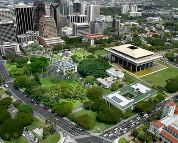 The Hawaii State Legislature governs from the Capitol, in the far right of this photo. Before 1969, it governed from Iolani Palace (surrounded by the lush greens in the foreground).