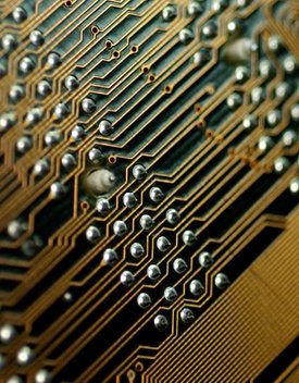 Close-up photo of one side of a motherboard PCB, showing conductive traces, vias and solder points for through-hole components on the opposite side.