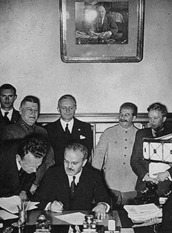 Molotov signs the German-Soviet non-aggression pact. Behind him are Ribbentrop and Stalin.