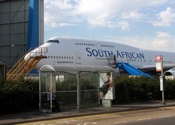 A London Transport bus stop with an unusual view, near London (Heathrow) Airport. The aircraft is a Boeing 747 of South African Airways