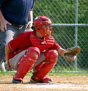 A baseball catcher prepares to receive the pitch