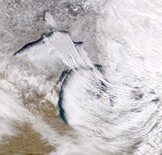 A cold air mass sweeping across  and  from the northwest collides with the moist air above the lakes and produces lake effect snow.