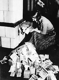 Inflation 1923-24: A woman in Germany feeds her tiled stove with money. The money is worth less than firewood.