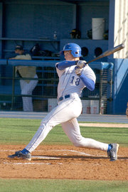 A batter follows through after swinging at a pitched ball.